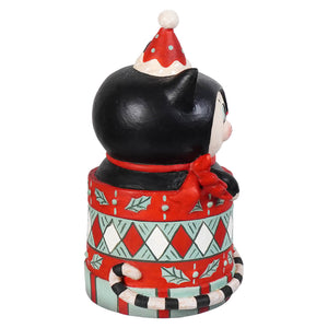 A black and white cartoon cat figurine wearing a red and white polka dot santa hat on a festive dezzy merry boo base by bethany lowe designs