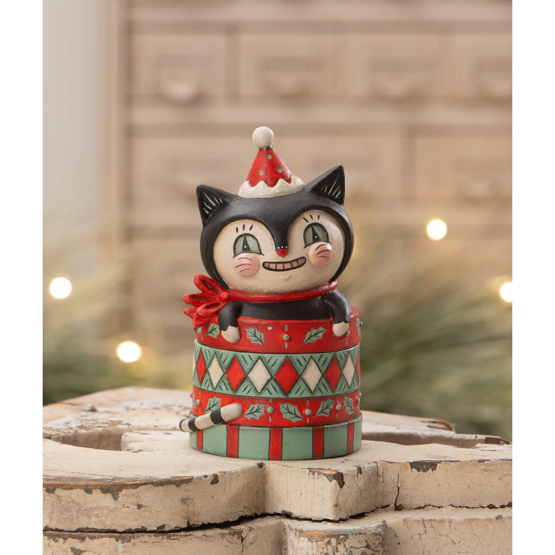 A black cat figurine with a red santa hat and scarf peeks from a festive dezzy merry boo gift box by bethany lowe designs