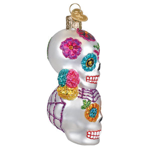 A vibrant glass sugar skull ornament with glittery flowers and purple webbing for figural decor and stacking skulls