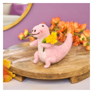 A soft pink felt dino critter holding yellow flowers perfect for valentine’s day figural decor and flowers critter gifts