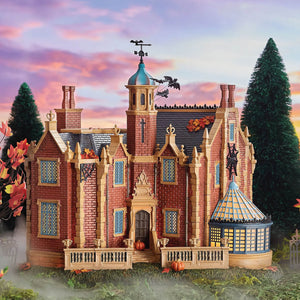 A detailed red brick disney haunted mansion miniature with blue windows bats pumpkins and spiderwebs for disney world fans