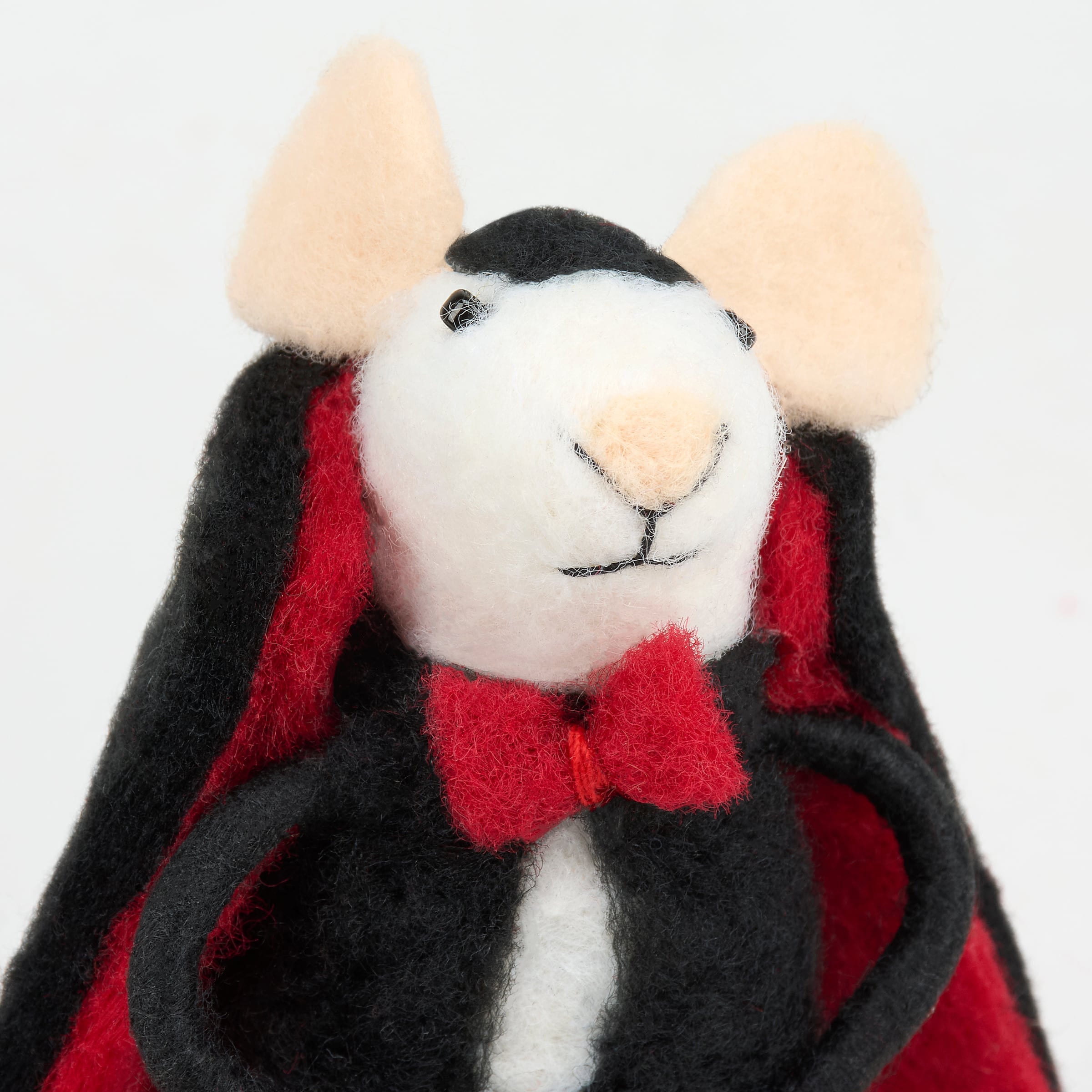 A white felt dracula mouse critter plush toy wearing a black and red velvet cape with a matching bow tie