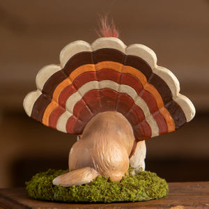 A bethany lowe dressed up tommy ceramic turkey with a striped fan tail standing on green moss