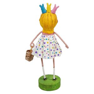 Decorative figurine wearing a polka dot dress, yellow hair with colorful crown, and carrying a basket while standing on a green base.