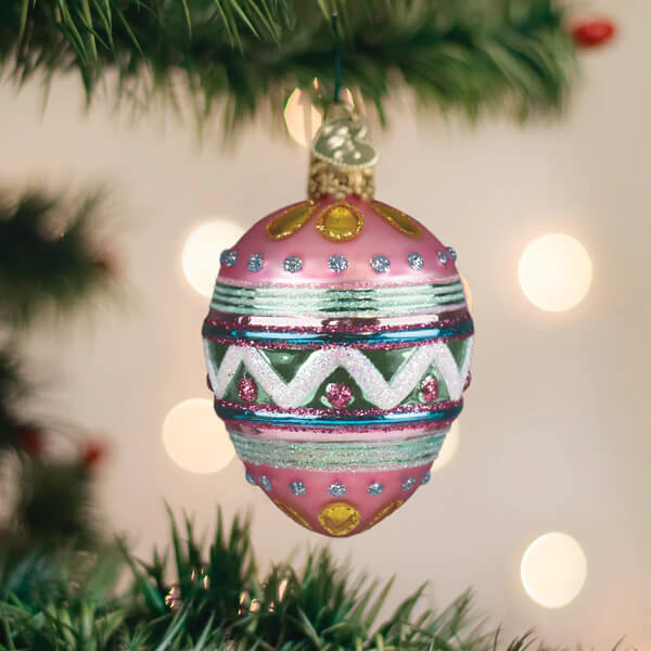 A pink glass christmas glass ornament with glittery green blue white stripes and gold accents easter egg ornament