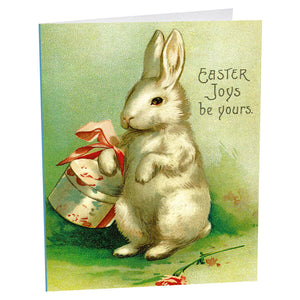 White rabbit sitting upright next to a decorated Easter egg.