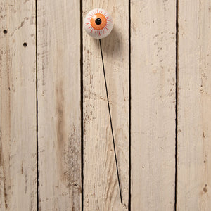 A white ceramic eyeball pick with orange iris and red veins on black metal rod from bethany lowe designs halloween picks