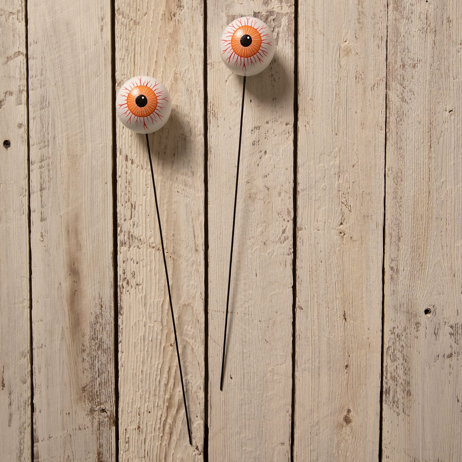 Two white plastic halloween garden stakes with orange and black eyeball design and red lines from bethany lowe designs halloween garlands wreaths and picks