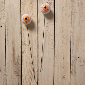 Two white plastic halloween garden stakes with orange and black eyeball design and red lines from bethany lowe designs halloween garlands wreaths and picks