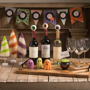 Three wine bottles with colorful spooky eyeball wine bottle stoppers in a bottle adornments set of 3