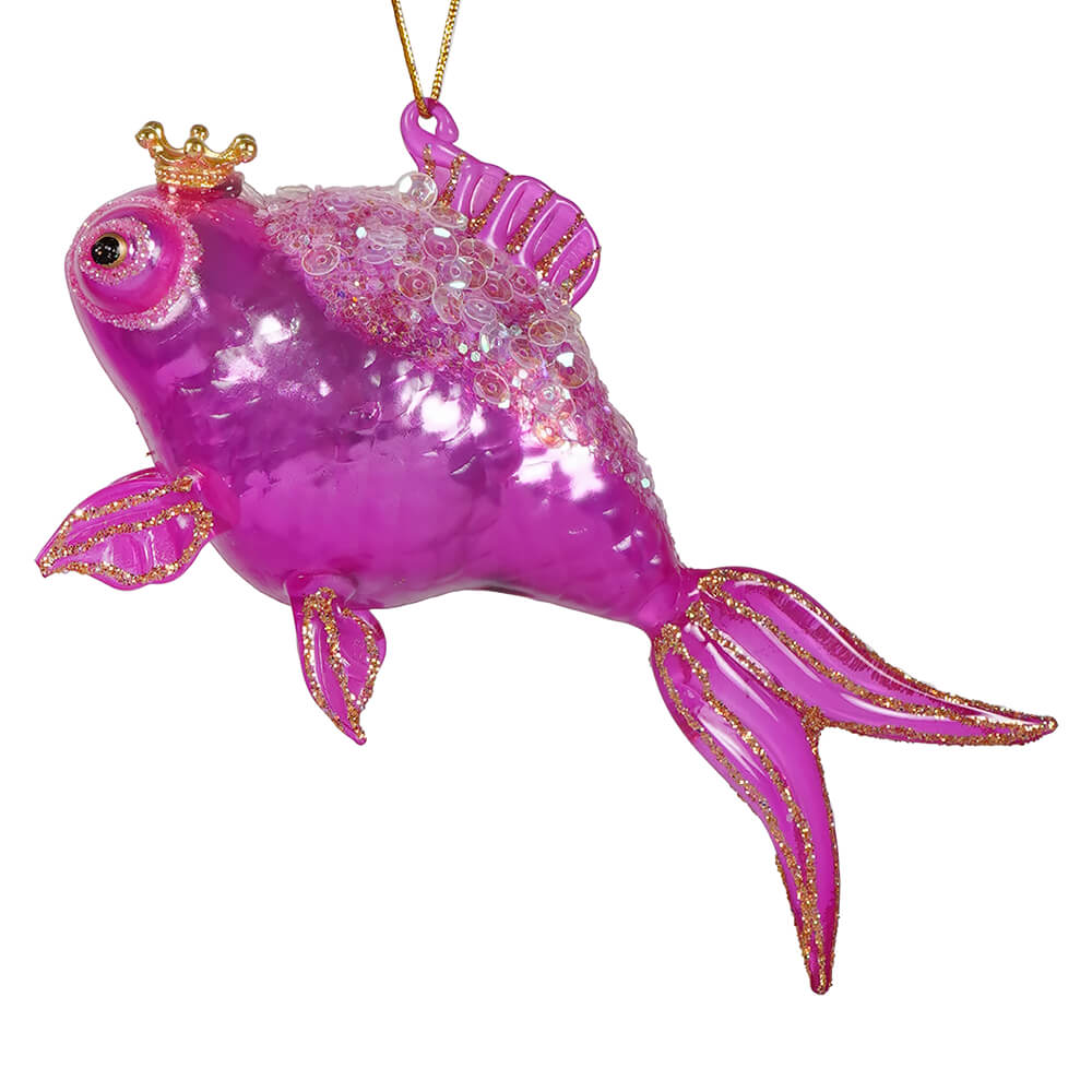 A vibrant pink glass goldfish ornament with gold glitter detailing and a tiny golden crown