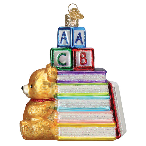 Golden teddy bear with red scarf sits beside colorful glass books and alphabet blocks in favorite children’s books book club ornament