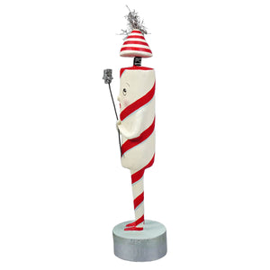 A whimsical candy cane-themed firecracker figure with red and white stripes holding a sparkler and tinsel hat