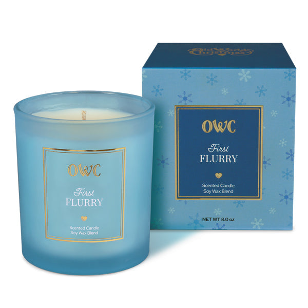 A translucent light blue glass candle jar with white soy wax blend labeled first flurry by owc perfect for a creative co-op candle set