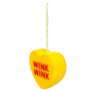 Yellow heart-shaped candy with ’WINK WINK’ text written in red.