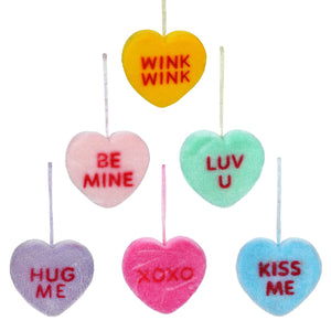 Colorful heart-shaped candy decorations with romantic messages like ’Wink Wink,’ ’Be Mine,’ ’Luv U,’ ’Hug Me,’ ’XOXO,’ and ’Kiss Me.’