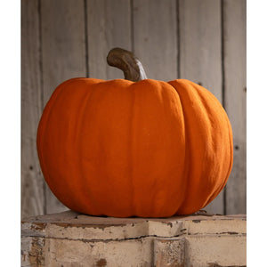 A bethany lowe flocked orange jol with a plush fabric surface and dark brown stem on a white wooden block