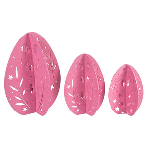 Three pink decorative eggs with floral and star cutout patterns.