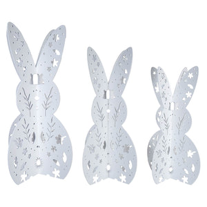 Three decorative white bunny silhouettes with floral cutout patterns.