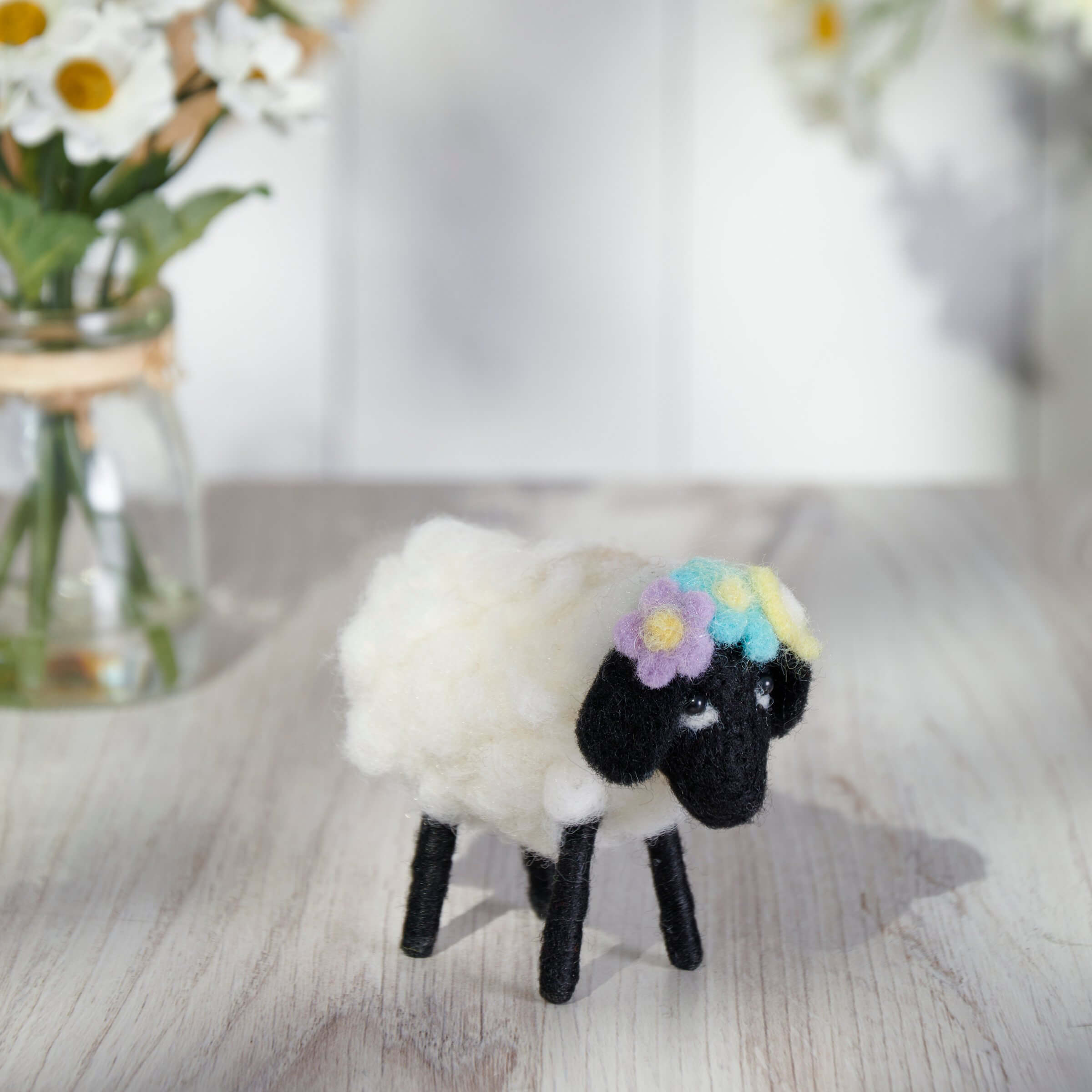 Black and white plush sheep wearing a pastel flower crown.