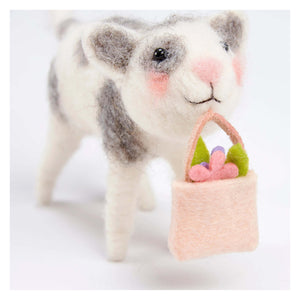 A charming white and gray felt cat critter holding a peach felt basket with flowers perfect for easter and spring tabletop decor