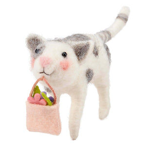 A charming white and gray felt cat critter holding a pink basket with colorful flowers for easter and spring tabletop decor