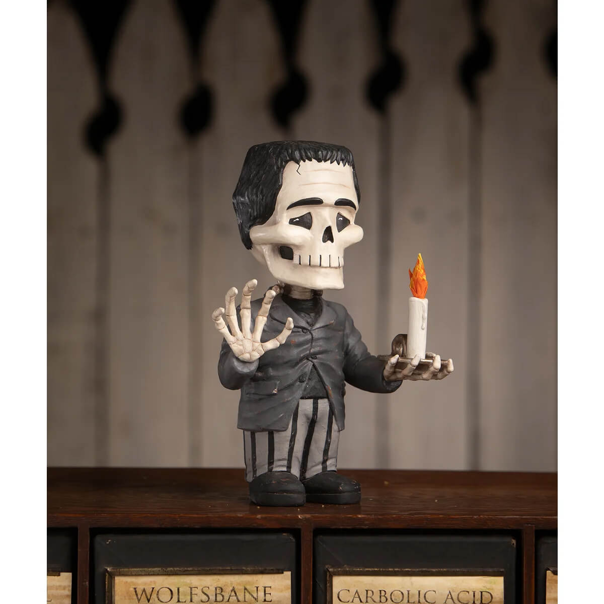Franken skelly bobblehead with black hair, white skull face, gray suit, holding an orange-flamed candle