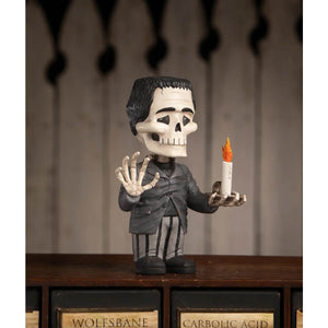 Franken skelly bobblehead with black hair, white skull face, gray suit, holding an orange-flamed candle