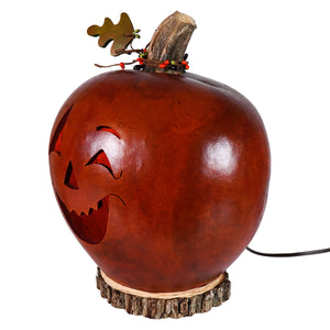 A rustic amber brown large lighted jack o lantern gourd with wooden stem and leaf by meadowbrooke gourds artisans