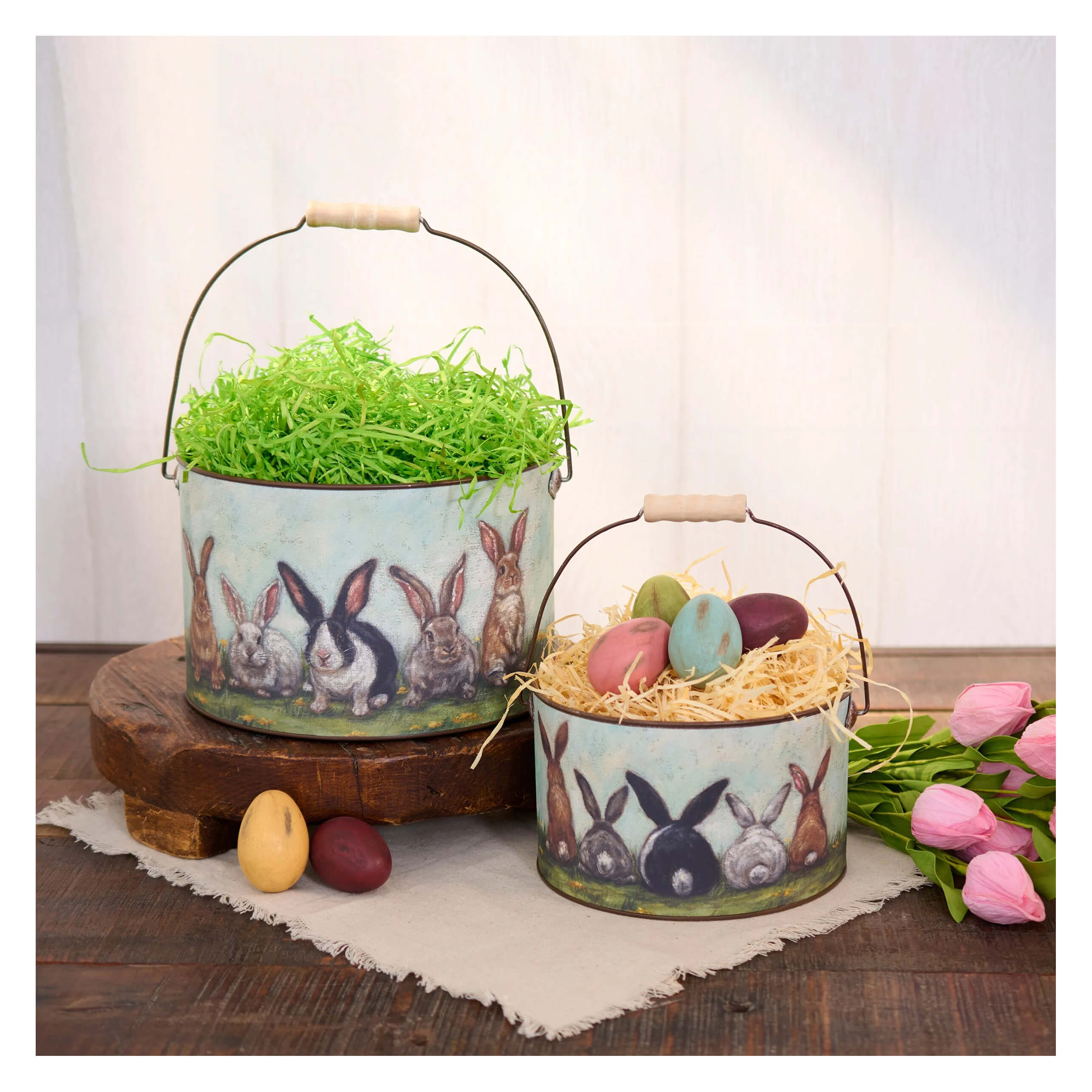 Two vintage-style metal easter buckets with painted rabbits filled with colorful eggs in friends bucket set