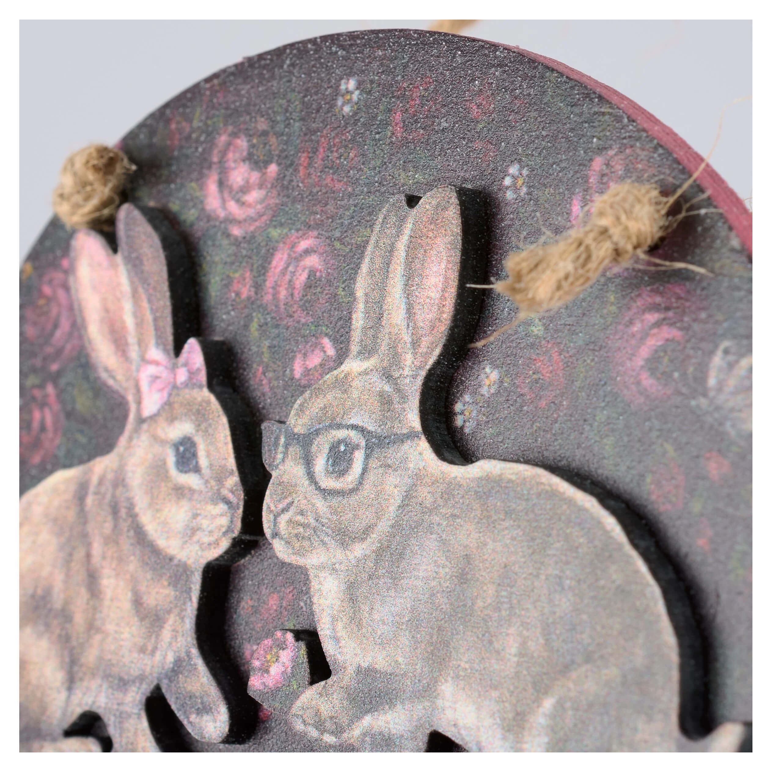 Circular wooden valentine’s day ornament with two illustrated rabbits on a dark rose patterned background