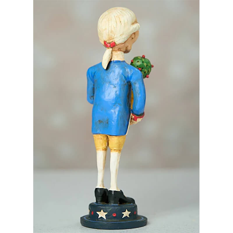 Painted figurine of a child in a blue dress holding something green behind their back while standing on a star-decorated base.