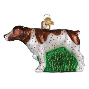 A glass christmas ornament shaped like a german shorthaired pointer dog with brown white speckled fur and green grass underside