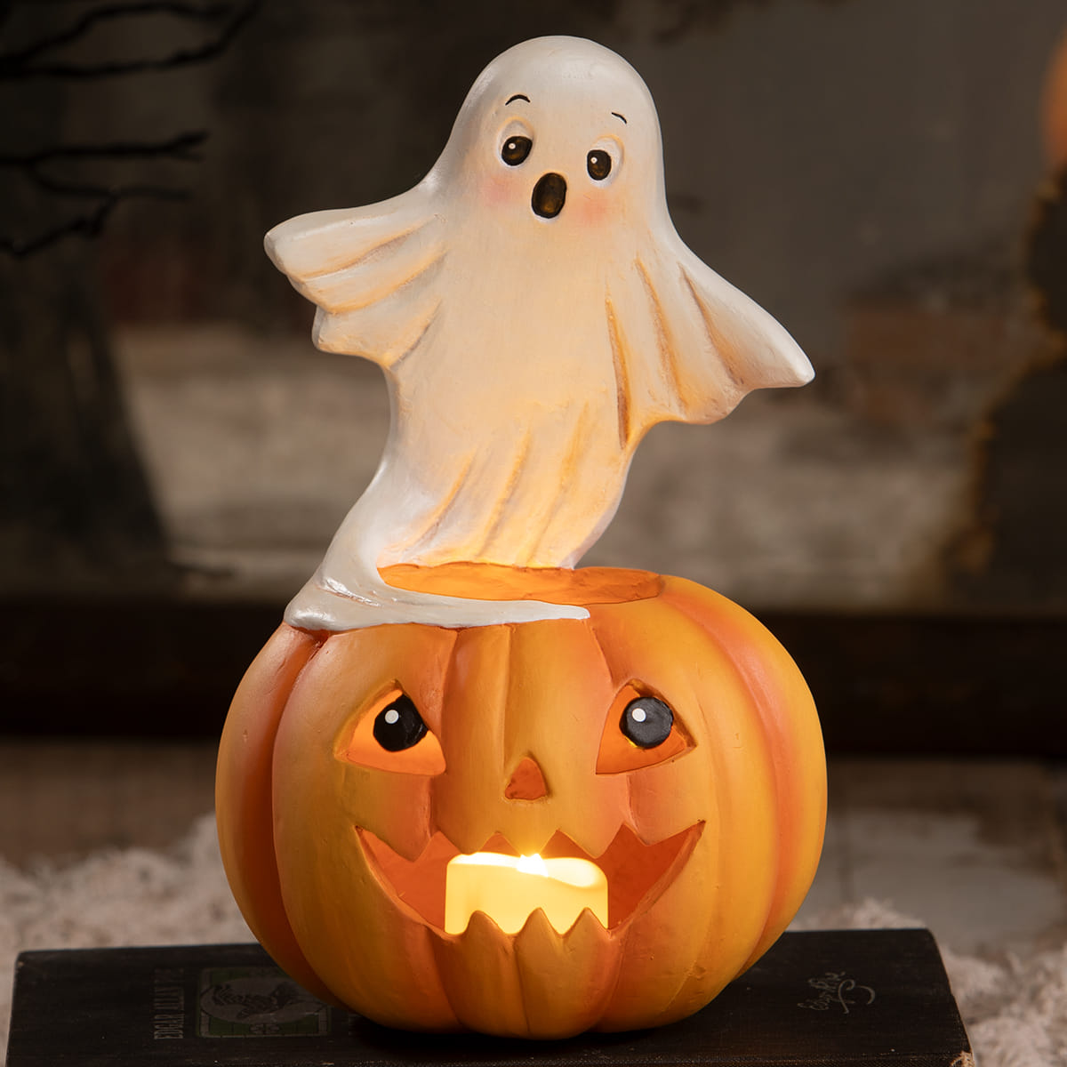 A glowing orange halloween pumpkin lantern with carved face and white ghost figure halloween ghost figures decor