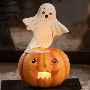A glowing orange halloween pumpkin lantern with carved face and white ghost figure halloween ghost figures decor