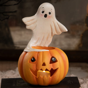 A cheerful orange halloween pumpkin lantern with glowing candle topped by a cute white ghost figure halloween ghost figures decor