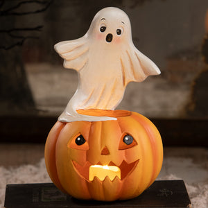 A whimsical orange jack o lantern with a glowing candle topped by a translucent white ghost figurine for halloween ghost figures decor and ornaments