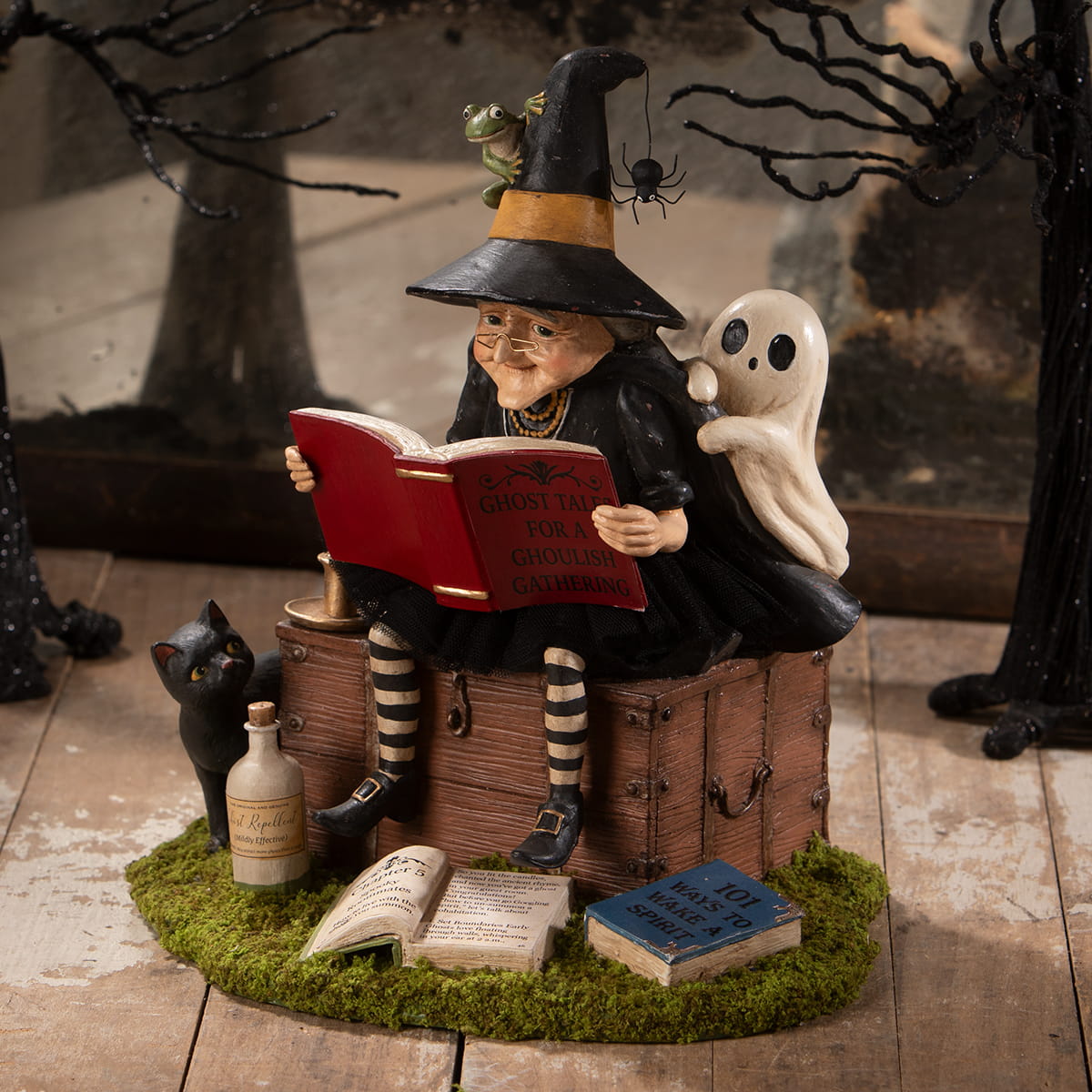 A whimsical halloween witches figurine in striped stockings reading a red book for witch decor and ghost stories
