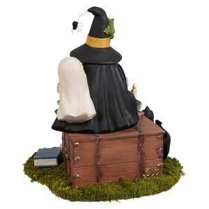 Black witch figurine with gold-trimmed hat featuring green frog and spider sitting beside white-robed figure halloween witches decor