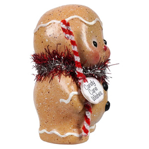 A charming gingerbread boy figurine with speckled tan surface white icing and tinsel spreading holiday cheer