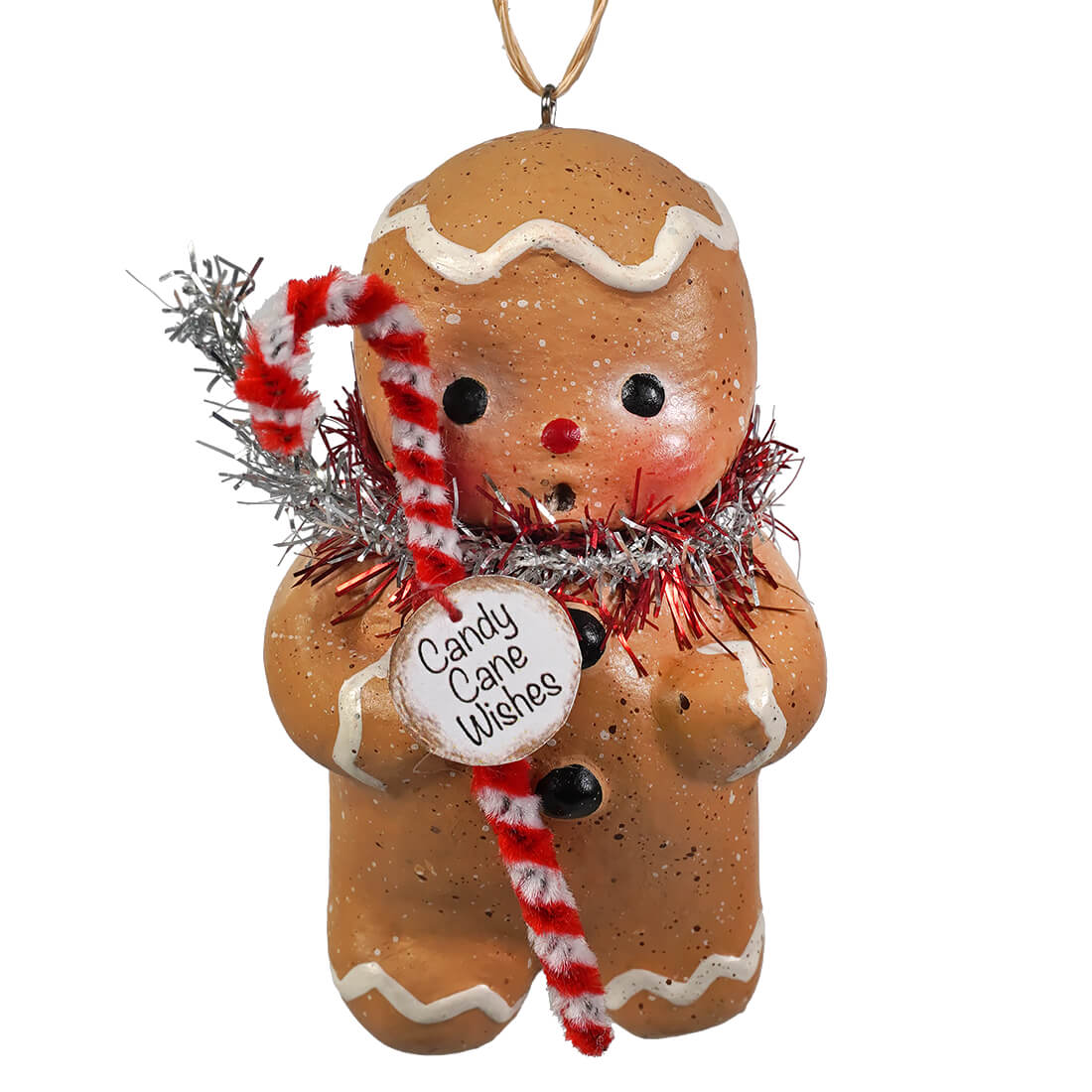 A festive gingerbread boy ornament by bethany lowe with white icing black button eyes and a candy cane wrapped in silver tinsel