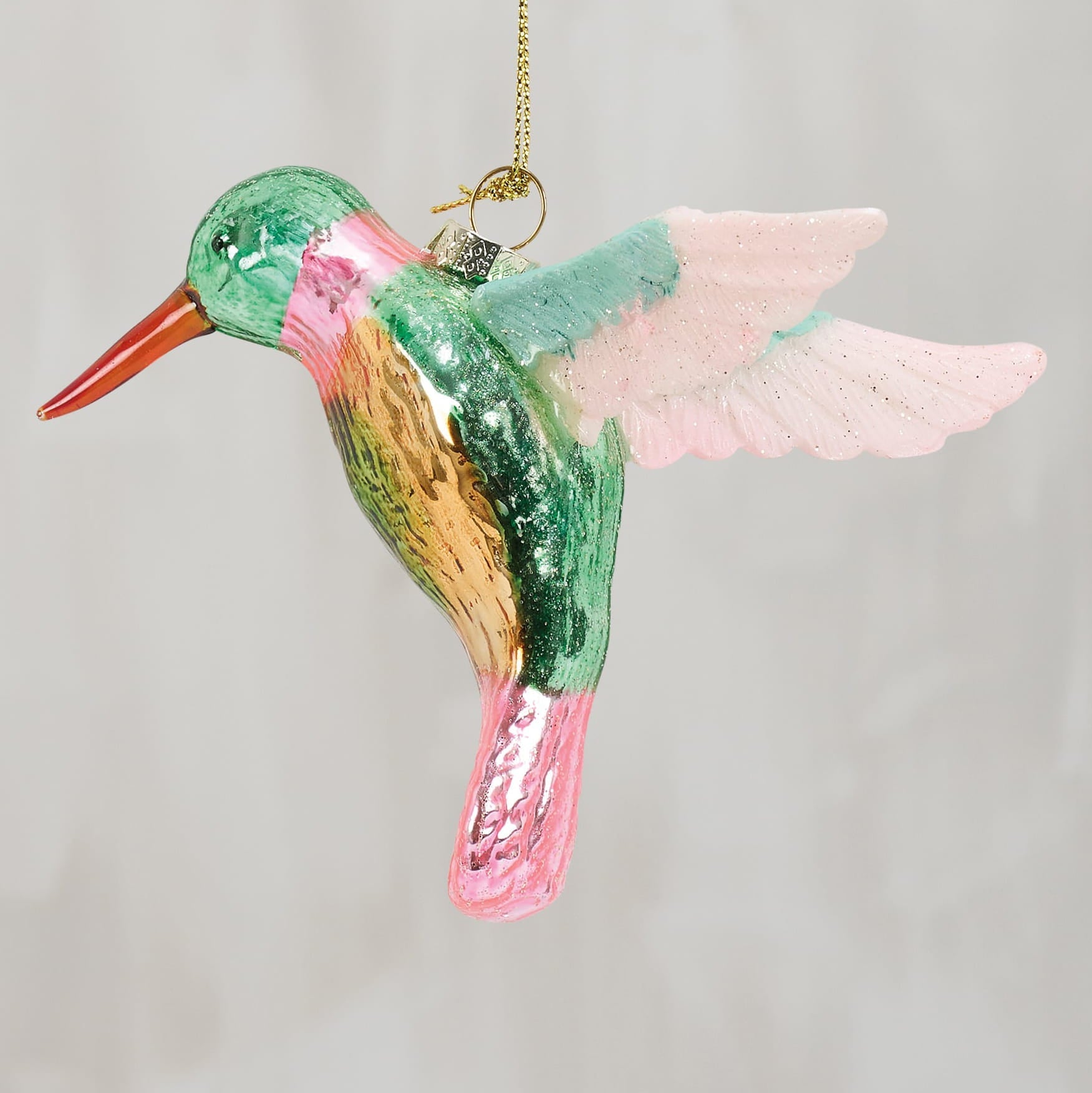 A vibrant glass hummingbird ornament with green body, pink wings, and orange beak perfect for decoration