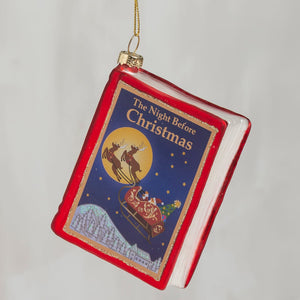Red glass storybook ornament shaped like a book titled the night before christmas with santa sleigh scene