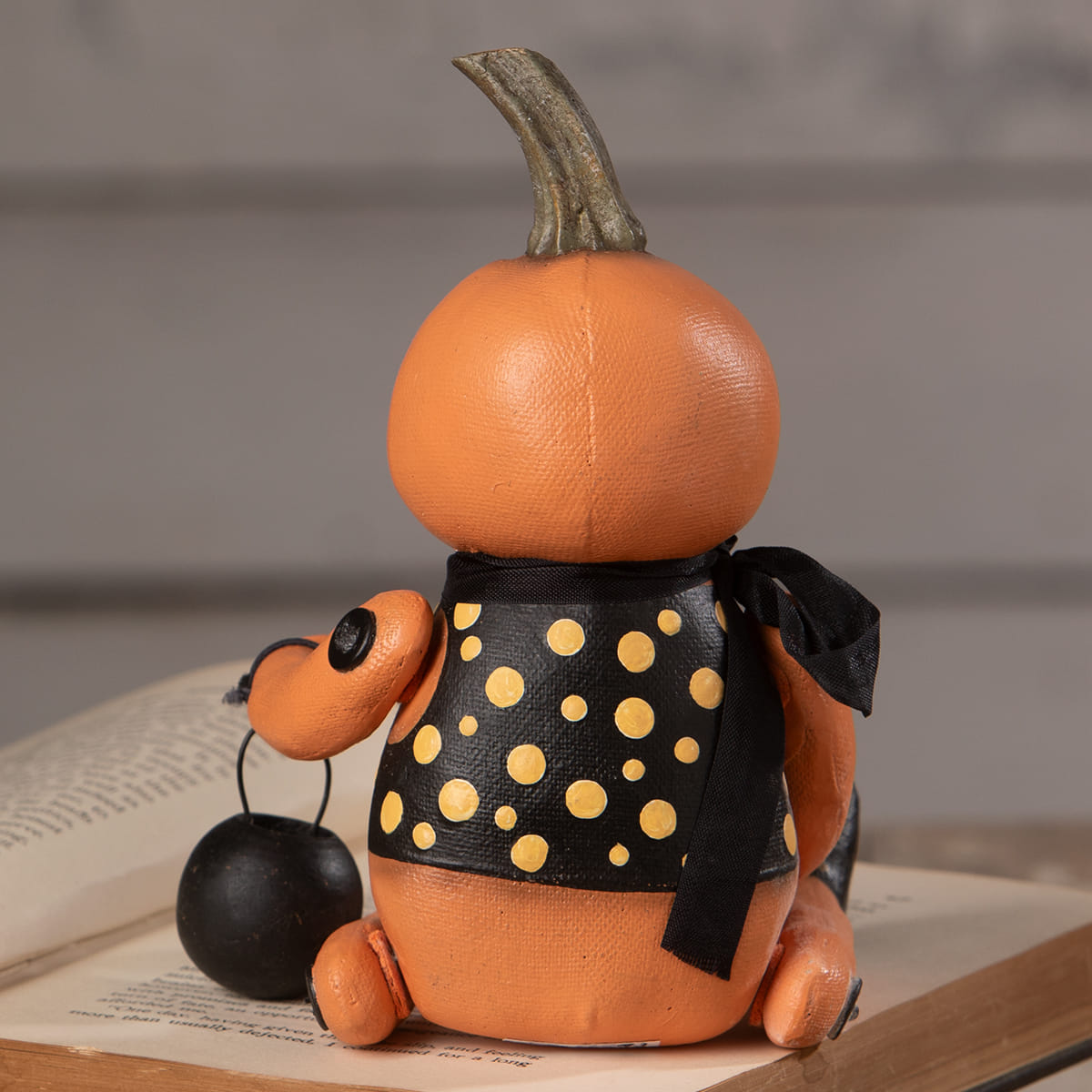 Orange pumpkin sitter figurine wearing black polka-dot dress with yellow dots and black ribbon sash by bethany lowe halloween figures & dolls
