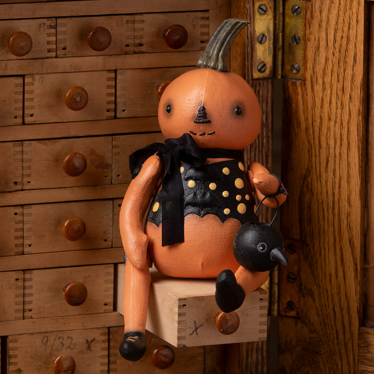 Orange pumpkin sitter doll wearing black polka-dot dress holding small black bird by bethany lowe halloween figures and dolls