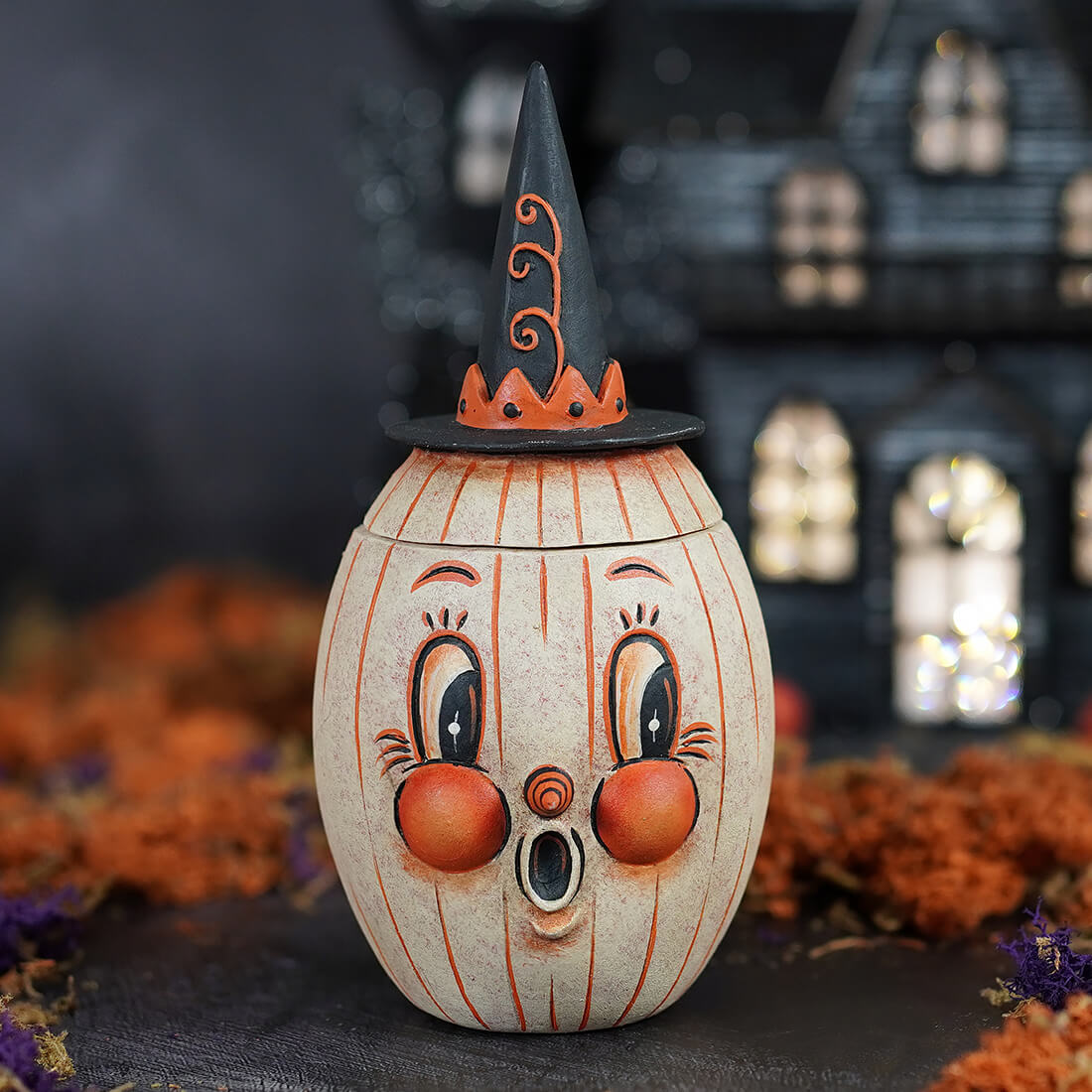 A charming cream ceramic gourdy white-o-ween pumpkin jar with orange stripes rosy cheeks and a witch hat perfect jack o lantern decor