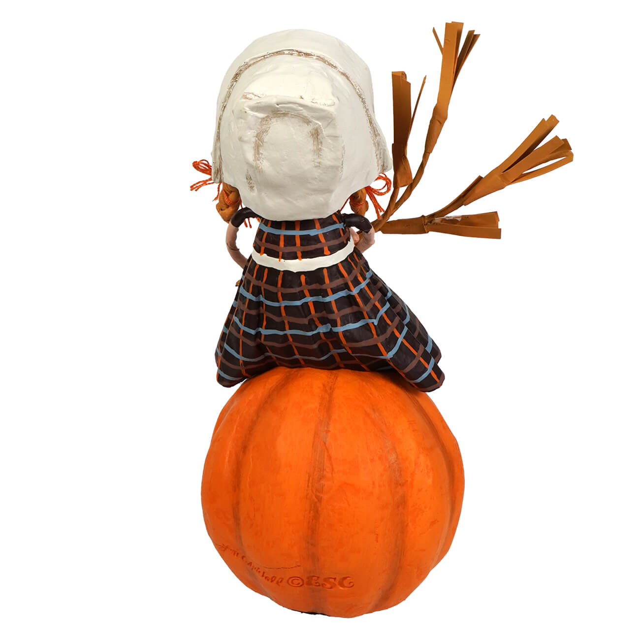 A whimsical paper mâché doll named grateful greta by lori mitchell with white bonnet and plaid dress on an orange pumpkin