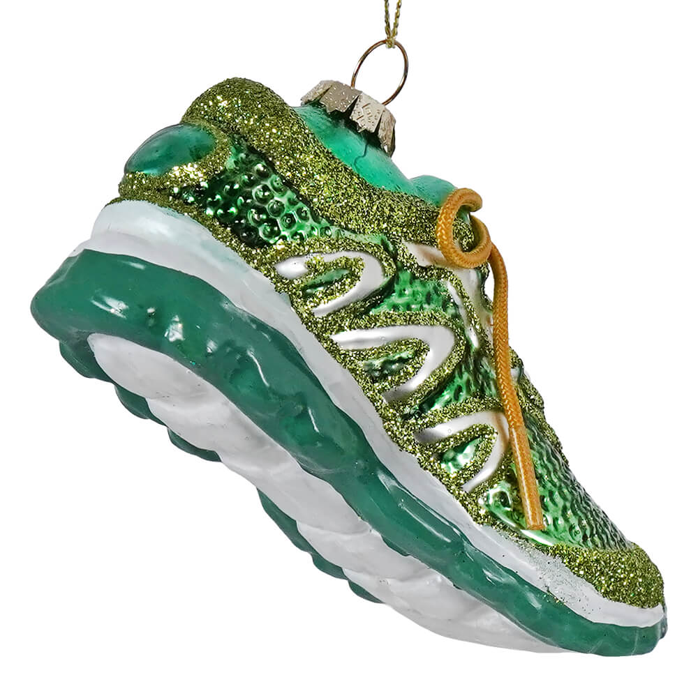 A glittery green running shoe ornament with white details gold laces and a metallic hanging loop for decoration