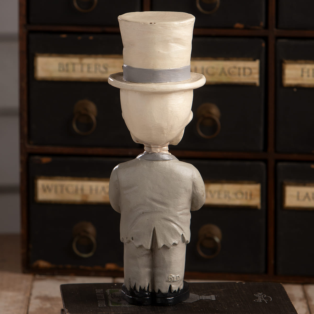 White sculpted skelly skeleton decor figure wearing a gray band top hat and matching suit called groom mortimer skelly