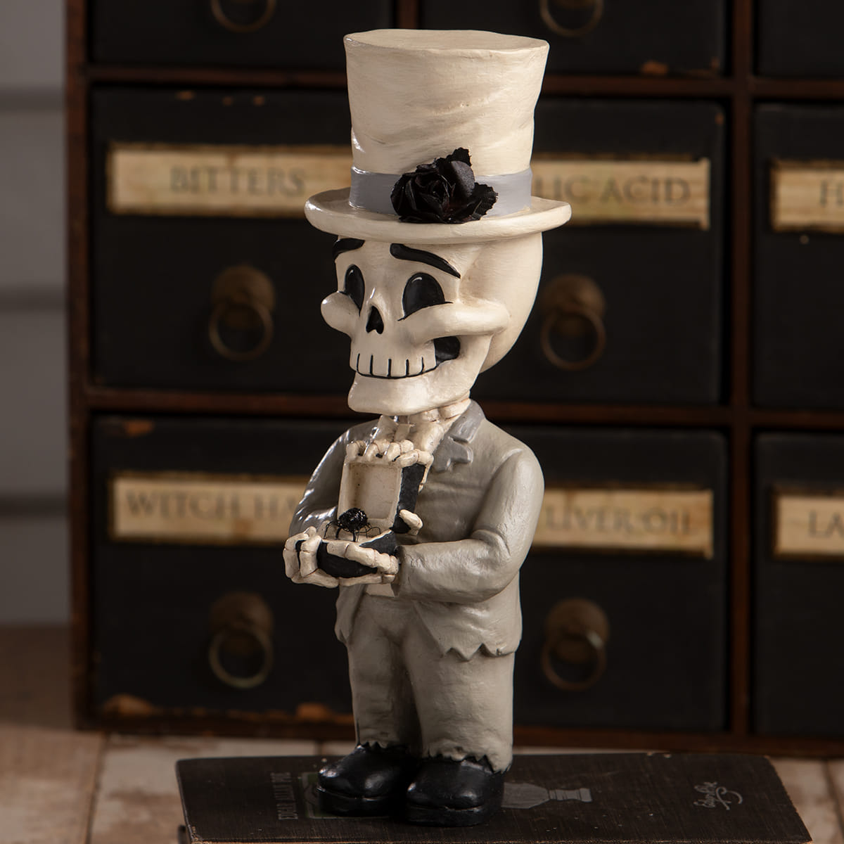 Groom mortimer skelly skeleton decor figure in gray suit and top hat with black rose holding small object